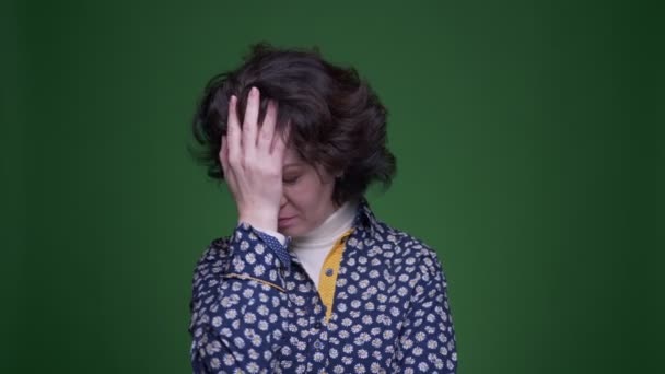 Closeup portrait of old caucasian brunette female malinmg a face palm being embarrassed and annoyed looking at camera with background isolated on green — Stock Video