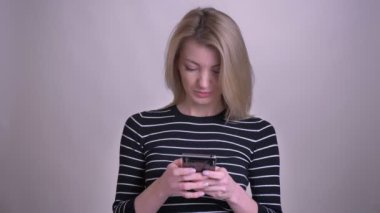 Telefonu kullanarak ve beyaz izole arka plan ile gülümseyen kamera bakarak yetişkin çekici sarışın beyaz kadın Closeup portre