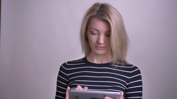 Close-up portret van volwassen aantrekkelijke blonde blanke vrouw met behulp van de Tablet en het tonen van groen scherm naar camera glimlachen met achtergrond geïsoleerd op wit — Stockvideo