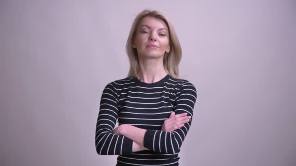 Крупный план портрета взрослой привлекательной белокурой белокурой женщины, перекрестившейся через грудь, глядя в камеру на фоне изолированного на белом фоне — стоковое видео