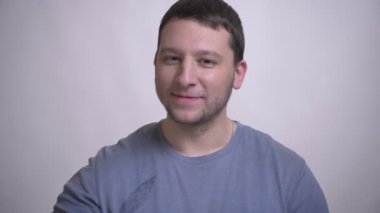 Yetişkin çekici beyaz adamın başparmağını yukarı doğru gösteren ve beyaz üzerine izole arka planlı kameraya mutlu bir şekilde bakan yakın çekim portresi