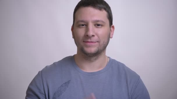 Primer plano retrato de adulto atractivo hombre caucásico mostrando dos dedos signo y sonriente mirando a la cámara con fondo aislado en blanco — Vídeos de Stock