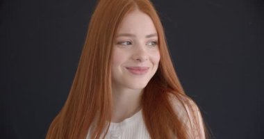 Siyah arka plan üzerinde kameraya mutlu bir şekilde gülümseyen güzel zencefil modelinin yakın çekim portresi.