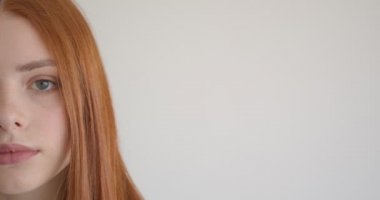 Beyaz arka planda kameraya sakin ve dikkatle izleyen güzel zencefil modelinin yarım yüz portresi.