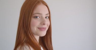 Beyaz arka planda kameraya flört gülümseme ile izlerken güzel zencefil modeli profil portresi.