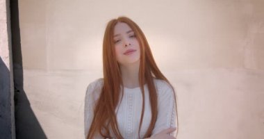 Güzel zencefil modeli beyaz duvar arka planda kamera içine flört gülümseme ile poz.
