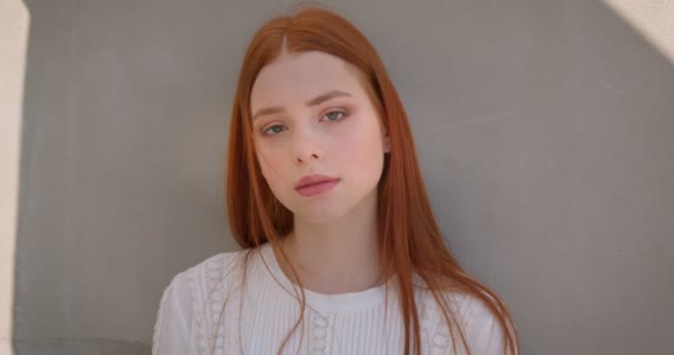 Pretty Young Ginger modell flirta med kamera lutande på den vita väggen. — Stockvideo