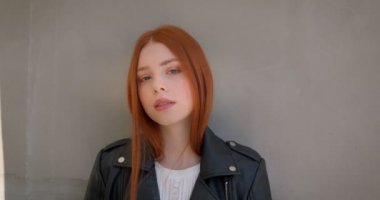 Beyaz duvara yaslanmış kamera ile flört deri ceket Cool genç zencefil modeli.