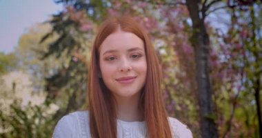 Pembe çiçek libahçede rüya gibi izleyen beyaz bluzla büyüleyici zencefilli kız öğrenci.