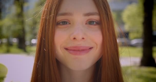 Close-up retrato de menina de gengibre sorrindo para a câmera feliz no parque verde . — Vídeo de Stock