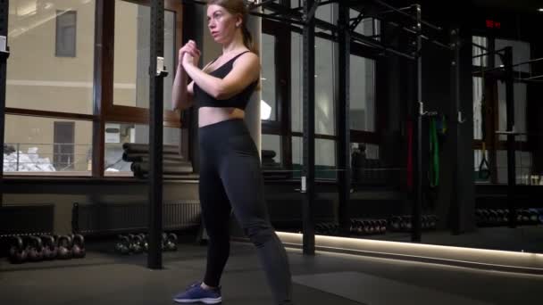 Joven deportista motivada haciendo sentadillas profundas en el gimnasio . — Vídeos de Stock