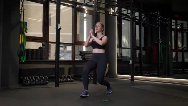 Jong gemotiveerd sportmeisje doet lunges wordt geconcentreerd in de sportschool. — Stockvideo
