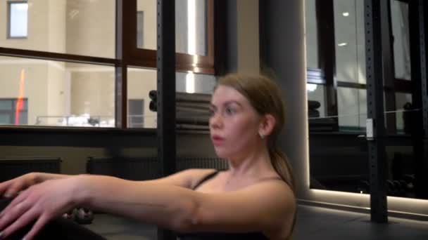 Gros plan d'une sportive concentrée fatiguée qui fait des craquements abdominaux avec son téléphone portable couché à proximité dans un gymnase . — Video