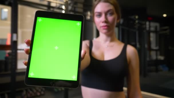 Close-up shot van Sportvrouw met paardenstaart toont tablet met Chromakey groen scherm wordt positief in de sportschool, — Stockvideo