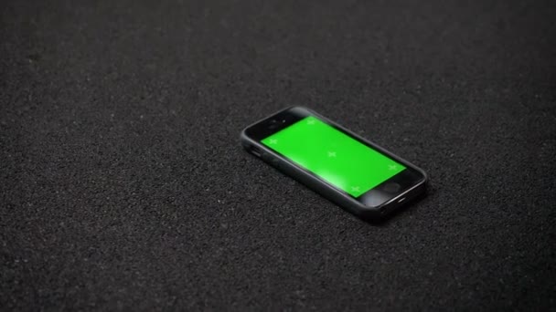 Das Handy mit dem grünen Chromakey-Bildschirm auf dem Boden in der Turnhalle liegend. — Stockvideo