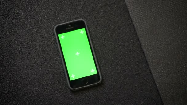 Közelkép shot okostelefon chroma zöld képernyő fekvő közelében cipők a karrimat edzőteremben. — Stock videók