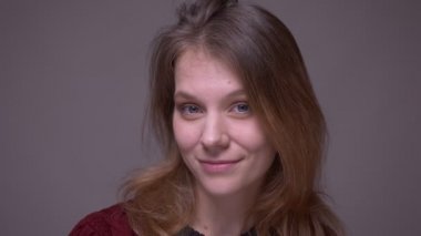 Genç kız öğrenci nin gri arka planda kamerayla eğlenceli bir şekilde flört ve ogling portresi.