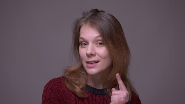 Mooie vrouwelijke jonge vlogger praat in camera actief op grijze achtergrond. — Stockvideo