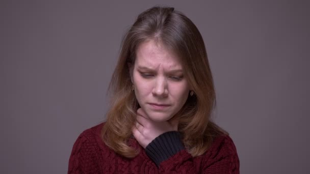 Portret van depressieve jonge vrouwelijke student met een zere keel en krassen haar nek op grijze achtergrond. — Stockvideo