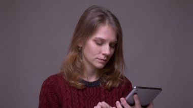 Neşeli kız öğrenci tablette uygulamayı değiştirir ve gri arka planda yeşil renk ekranı gösterir.