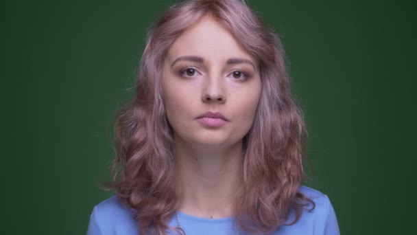 Close-up shoot of extraordinary model with wavy long hair watching calmly into camera on green chroma background. — Stock Video