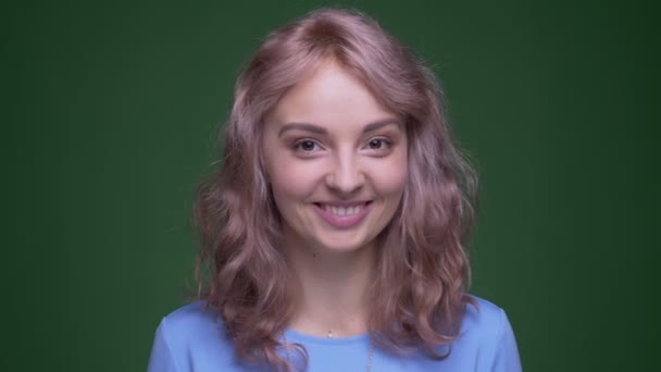 Beautiful model with wavy long hair smiles happily into camera being very surprised on green chroma background. — Stock Video