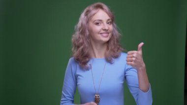 Dalgalı uzun saçlı güzel model yeşil renk arka plan üzerinde başparmak koyar.