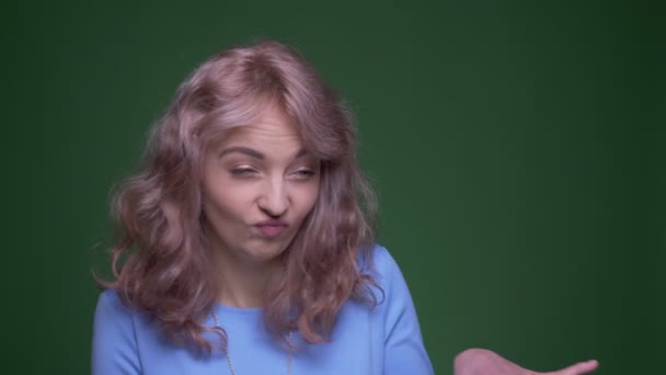 Bellissimo modello con capelli lunghi ondulati che ballano stranamente gioiosi su sfondo cromatico verde . — Video Stock