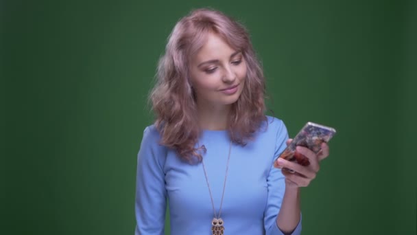 Hermoso modelo con sonrisas onduladas de pelo largo haciendo selfies en el teléfono inteligente sobre fondo de croma verde . — Vídeos de Stock