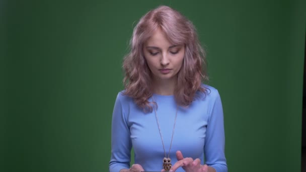 Beau modèle avec des sourires ondulés de cheveux longs montrant écran bleu de la tablette sur fond vert chromé . — Video