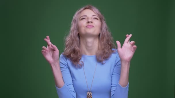 Gyönyörű modell hullámos, hosszú haj imádkozik keresztbe ujjaival a zöld chroma háttér. — Stock videók