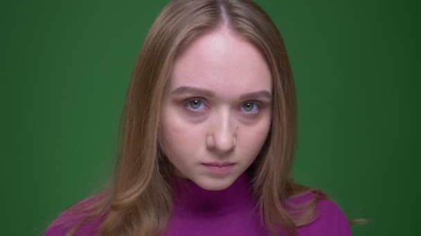 Portrait of beautiful ginger student watching fixedly and calmly into camera on green chroma background. — Stok Video