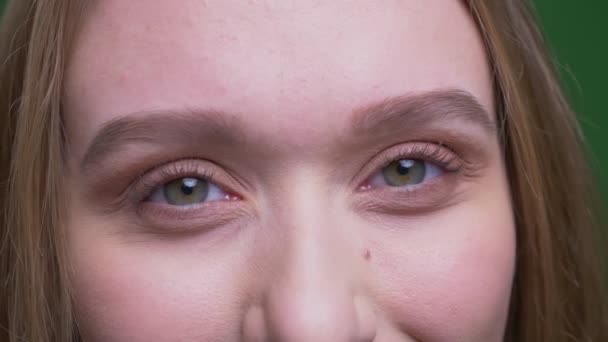 Retrato ocular de una bonita estudiante de jengibre sonríe alegremente en la cámara sobre fondo de croma verde . — Vídeos de Stock