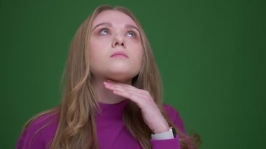 Üzgün zencefil kız öğrenci yeşil krom arka plan üzerinde boğaz ağrısı olan boynuna dokunarak.