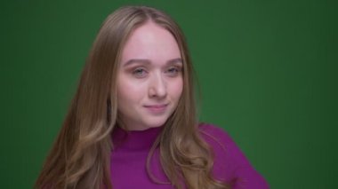 Güzel zencefil kız öğrenci yeşil renk arka plan üzerinde garip dans hareketleri yapar.