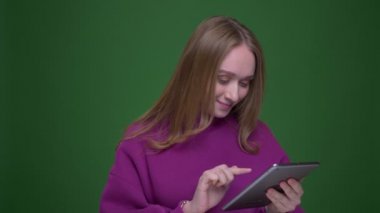 Güzel kadın zencefil vlogger tablet üzerinde uygulama açar ve yeşil renk arka plan üzerinde mavi ekran gösterir.