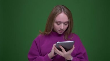 Güzel kadın zencefil vlogger yeşil renk arka plan üzerinde sevinçle tablet mavi ekran gösterir.