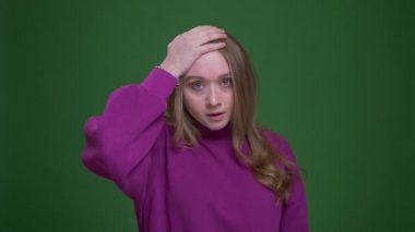 Pretty zencefil kız öğrenci yeşil renk arka plan üzerinde tahriş ve sıkıntı göstermek için facepalm jest yapar.