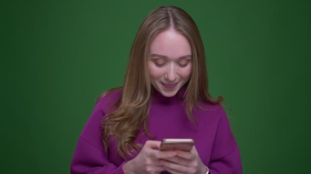 Красивая женщина рыжая студентка работает со смартфоном быть внимательным и рад на зеленом фоне хромы . — стоковое видео