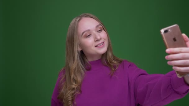 Jolie étudiante gingembre parlant selfies sur smartphone sur fond de chroma verte . — Video