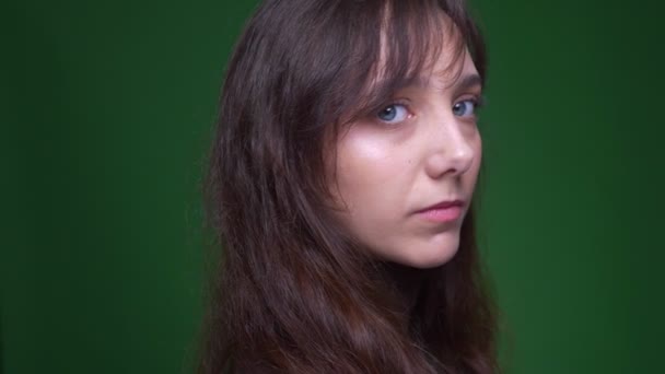 Ung brunett kvinnlig student förvandlas till kamera och ser fredligt i det på grön bakgrund. — Stockvideo