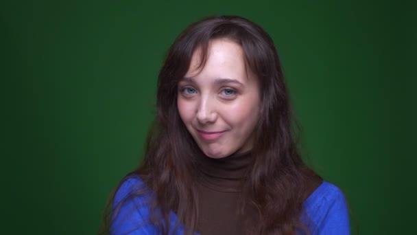 Mladá brunetka studentka je přátelský a pozitivní otáčí hlavu nesouhlasit do kamery na zeleném pozadí. — Stock video