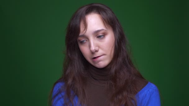 Ung brunett kvinnlig student att vara förvirrad och tankeväckande klockor runt på grön bakgrund. — Stockvideo