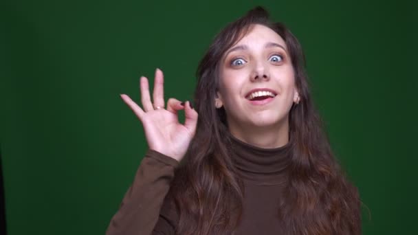 Ung brunett affärskvinna gör ok gest för att visa tillfredsställelse och glädje på grön bakgrund. — Stockvideo
