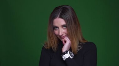 Kestane ile Mütevazı iş kadını çenesini dokunur ve yeşil arka plan üzerinde kamera ile flört.