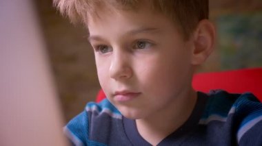 Evde konsantre olan dizüstü bilgisayar ile çalışan sevimli küçük çocuk Close-up dolly çekim.