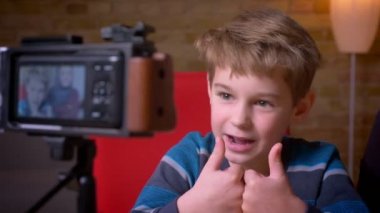 Joyful küçük çocuk ve hijab kayıt video onun Müslüman annesi kamera objektifinde shot thumbs-up ile vloggers olarak video.