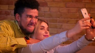 Afrikalı adam ve beyaz kız telefonda selfie fotoğrafları çekerek komik yüzler sevinçle ve gülüyor yapma.