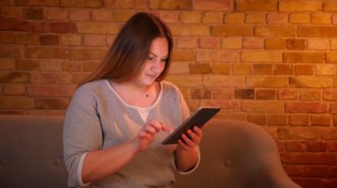 Rahat ev atmosferinde tablet ile hoş çalışan kilolu uzun saçlı kadın freelancer Portresi.