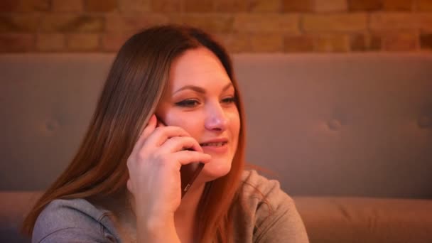 Nahaufnahme eines entspannten Plus-Size-Langhaarmodells, das auf dem Boden sitzt und in seinem gemütlichen Zuhause eine Sprachsteuerung auf dem Smartphone hat. — Stockvideo